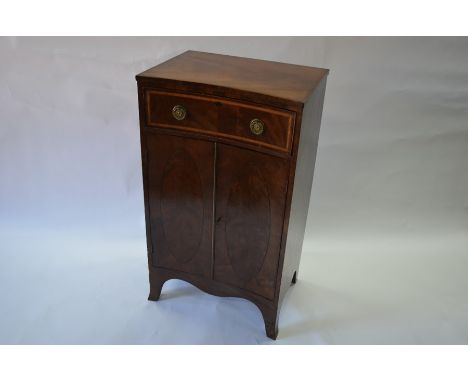 A Sheraton style mahogany inverted bow-front side cabinet, the frieze drawer with satinwood cross-banded fascia and round pla