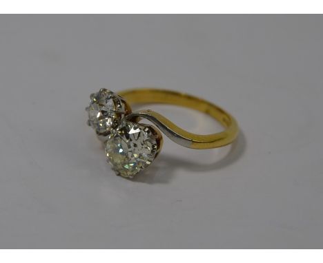A two-stone diamond crossover ring, the yellow and white gold shank stamped 178ct, one oval claw set old cut diamond approx 1
