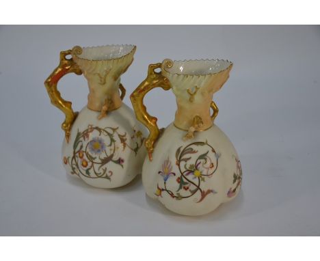 A pair of Victorian Royal Worcester jugs of lobed form with gilt organic handles, painted with scrolling floral designs on a 