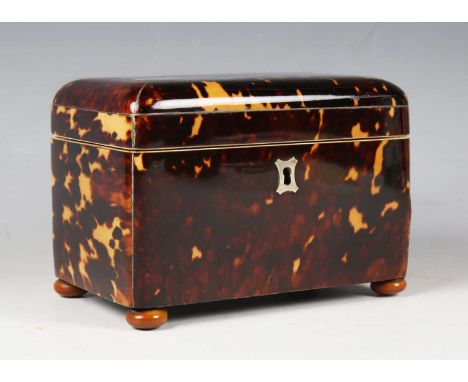 An early 19th century tortoiseshell tea caddy with metal stringing and vegetable ivory feet, the hinged lid enclosing two lid