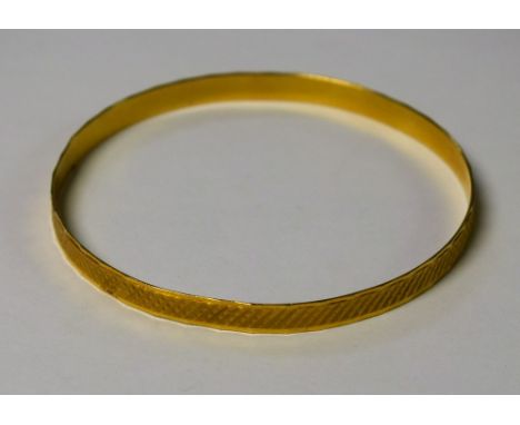 An 18ct gold fancy textured slave bangle, central embossed lattice, between plain polished edging strips, stamped 750-466MI, 