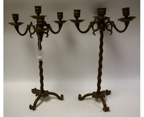A pair of cast brass adjustable three branch, four light, table candlesticks, upward scrolling mask head arms, tripod base, 4