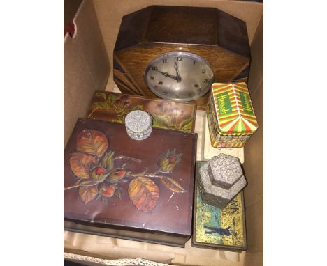 A box of old tins and a mantel clock. 