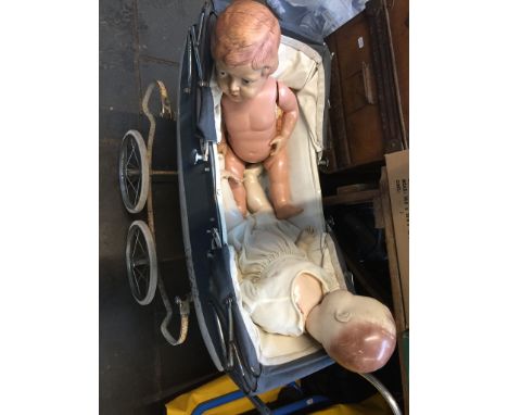 A vintage doll's pram containing a Palitoy plastic doll and another similar English doll. 