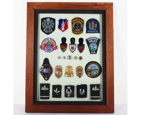 Framed Display of Foreign Police Badges: Large heavy frame of badges to include US gilt breast badges, enamel fob badges, but