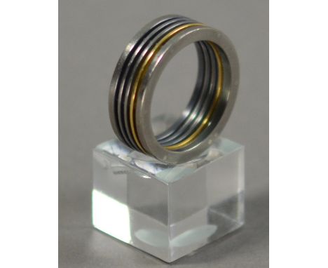 JOEL DEGEN (born 1944); a ring, stainless steel and titanium combined with 18ct gold, ring size Q.

Provenance: Purchased fro