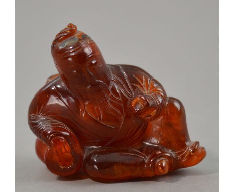 A Japanese carved amber netsuke modelled as a bearded gent reclining on two ceramic vessels, length 6cm. CONDITION REPORT: Da