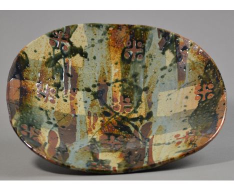 JOHN MALTBY (born 1936); a large stoneware press moulded footed dish, sponged and wax resist polychrome decoration to interio