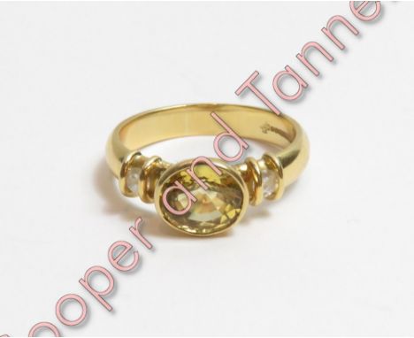 An 18 carat gold yellow sapphire and diamond ring, the oval cut with a diamond to each shoulder, finger size R ½, 6.2 g gross