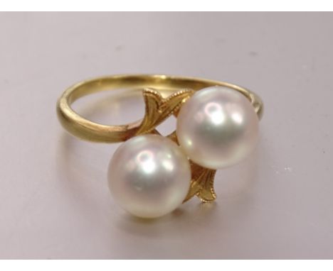 A crossover ring set two cultured pearls, the mount marked 'K18', size O½, 3.7g. 