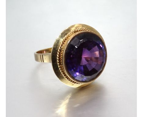 A large dress ring set round fancy-cut purple synthetic sapphire, in unmarked yellow gold mount, tests as 18ct approximately,