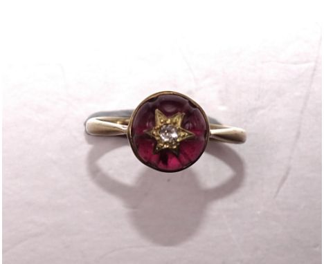 A Victorian 9ct gold ring collet-set a round garnet cabochon surmounted by an old-cut diamond-set star motif, size O, 2.7g. 