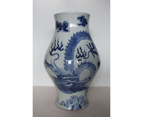 An unusual Chinese blue and white large bulbous jar decorated with a sinuous dragon chasing the flaming pearl, above foaming 