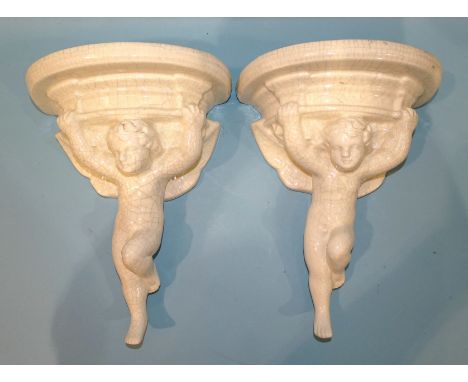 A pair of Poole-style ceramic crackle ware white pottery clock or wall brackets, each supported by a Putto, impressed mark Si