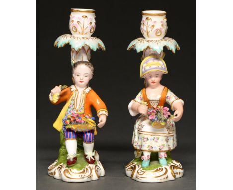 A pair of Sampson Hancock candlestick figures of a boy and girl with a basket of fruit or flowers, c1900, 18cm h, puce painte