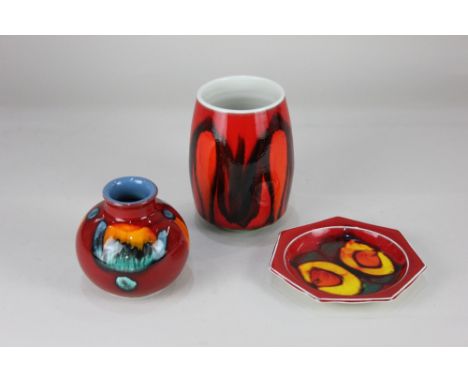 A Poole pottery baluster vase, brightly decorated on red ground, 11cm high, together with a similar Poole pottery tall vase, 