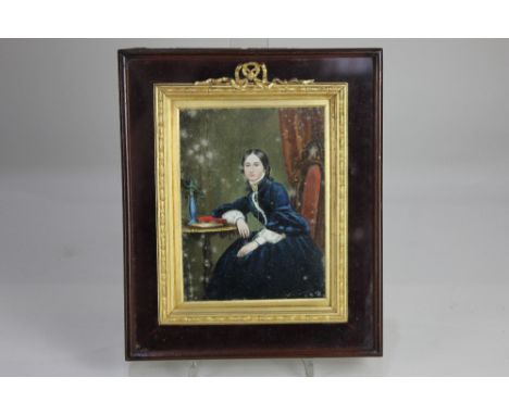 A 19th century miniature portrait of a lady dressed in blue velvet, seated beside a table, inscribed paper label verso 'Mrs H