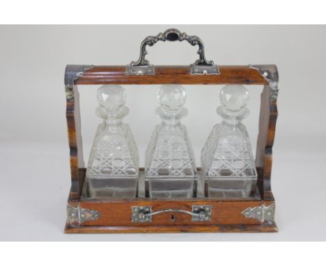 An oak three decanter tantalus, with white metal mounts, 37cm, no key