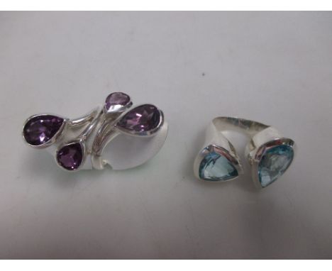 A blue topaz two stone statement ring and an amethyst ring in the same vein, the first asymmetrically set with a large pear c