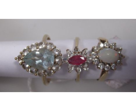 A ruby and diamond cluster ring 9ct London 1990 an opal and cubic zirconia cluster ring 9ct Edinburgh 1984 and an aquamarine 