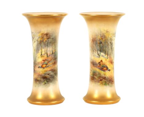 JAMES STINTON. A PAIR OF ROYAL WORCESTER GILT EDGED FLARED CYLINDRICAL CABINET VASES painted with unusual wooded and waterfal