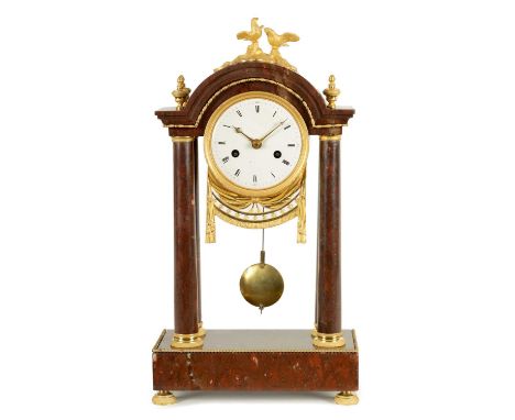 AN EARLY 19TH CENTURY FRENCH ROUGE MARBLE AND ORMOLU PORTICO MANTEL CLOCK the break arched top surmounted by two doves on sty