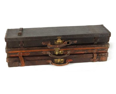 A COLLECTION OF THREE LEATHER AND CANVAS LINED SHOTGUN CASES with brass locks and fitted interiors, one having the original l