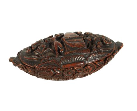 A 19TH CENTURY CARVED CAQUILLA NUT SNUFF BOX of oval lidded form with finely carved scrolled leafwork and seated dog beside a