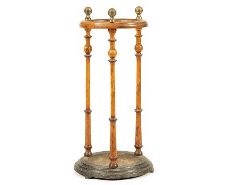 A 19TH CENTURY CIRCULAR WALNUT UMBRELLA/STICK STAND with slender tapering ringed uprights and turned brass finials, on a dish