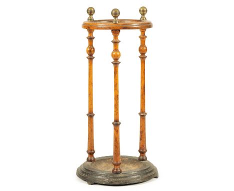 A 19TH CENTURY CIRCULAR WALNUT UMBRELLA/STICK STAND with slender tapering ringed uprights and turned brass finials, on a dish