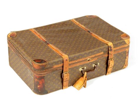 A VINTAGE LOUIS VUITTON SUITCASE with a monogram covering and tan leather straps78cm wide 53cm deep 25cm high