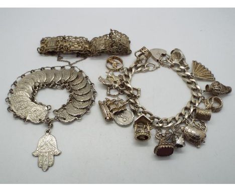 A silver charm bracelet with a quantity of white metal charms and two further white metal bracelets.