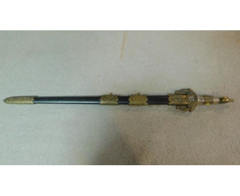 A Middle Eastern decorative sword with brass detailing and black scabbard.   W.91cm 