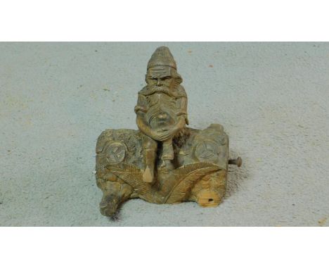 A 20th century Black Forest carved wooden stamp box and inkwell of a gnome sitting on a log. Half the log comes off to show f