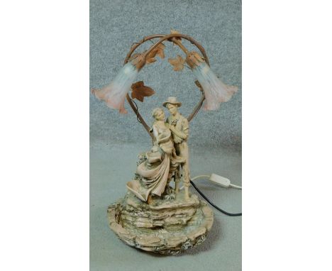 A stone effect water fountain light. It has trumpeting blown glass shades and depicts a young couple embracing. H.56cm 