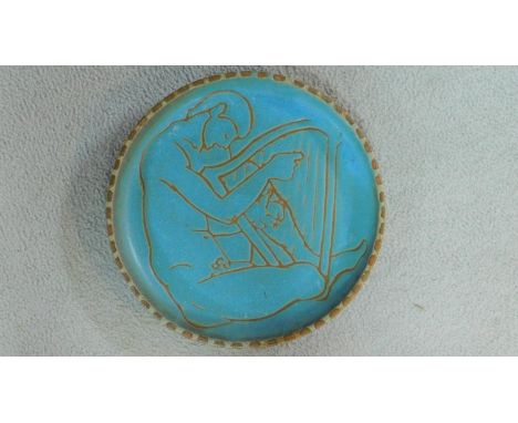 A mid century pale blue glazed studio pottery Sgraffito charger by London artist Lucy Rickards, depicting a male form playing