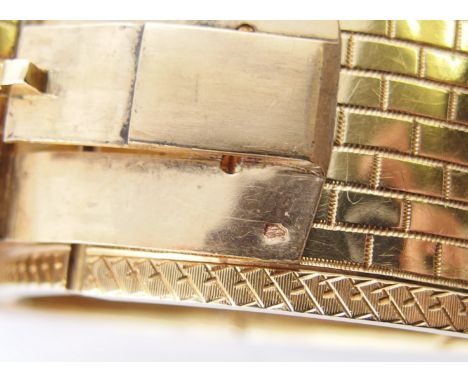 A French 18ct gold bangle the surface textured with an engraved brick pattern with a decorative border, with box clasp and sa