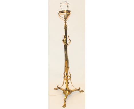 An Arts and Crafts brass standard lamp the adjustable column with scroll upright supports on tripod base, 142cm high