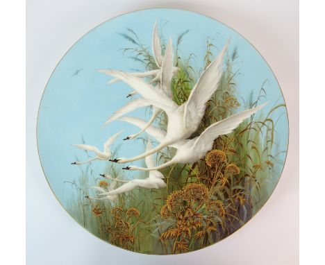 CHARLES H C BALDWYN (1859 - 1943) A circular Royal Worcester plaque finely painted with a flock of swans rising amongst gilt 