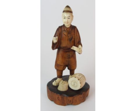 A Japanese carved wood and ivory okimono of a drummer standing and holding a note above a drum and tree stump, signed, 18cm h