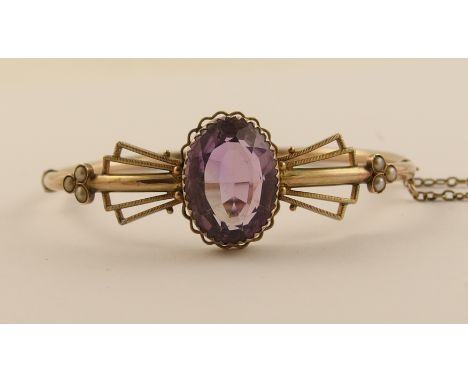 An amethyst Art Deco bangle with angular wing shapes framing the oval facet cut amethyst flanked with trefoils of split pearl