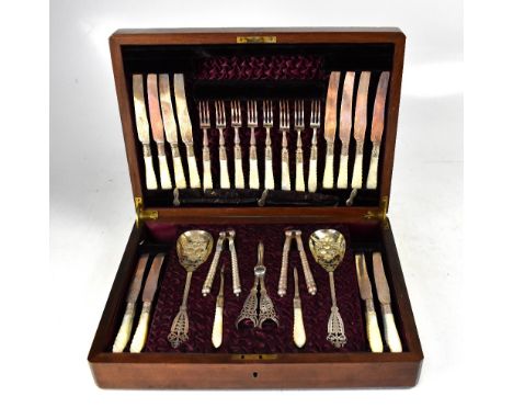 A late Victorian walnut cased dessert set comprising twelve knives and forks with wrythen twisted mother of pearl handles, a 