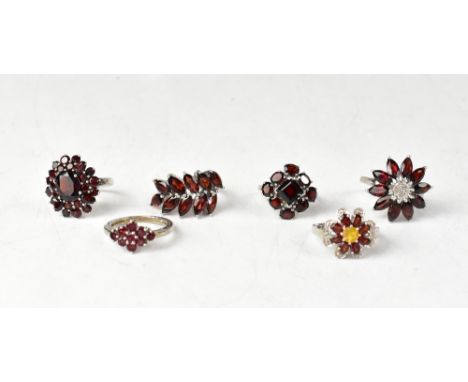 Six garnet and sterling silver rings, comprising a Mozambique garnet, with oval and round garnets in a floral cluster, size O