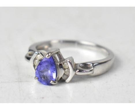 A modern 9ct white gold ring with three claw set pear-shaped tanzanites, flanked by three tiny diamonds to each shoulder, of 