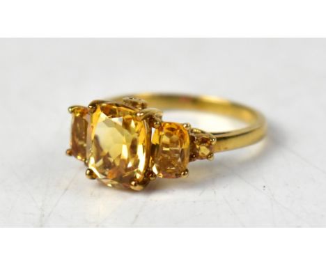 A 9ct yellow gold ring set with a central cushion cut citrine, flanked by two smaller oval citrines, further flanked by two s
