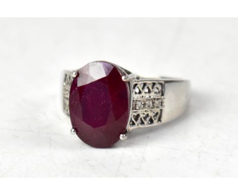 A 9ct white gold ring with claw set oval fissure-filled ruby, with a row of tiny diamonds with open trellis top and bottom de