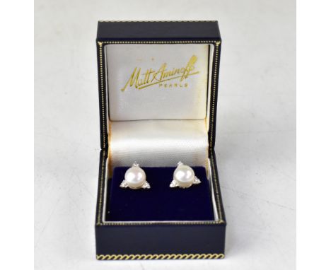 A pair of 18ct white gold Art Deco style earring studs, the central pearl with tiny diamond tipped triangles at each third, o
