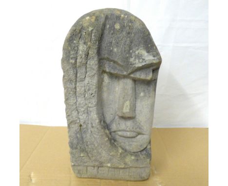 A contemporary carved Lake District stone sculpture of triangular form, a man's face over the word 'Peace', height 45cm, carv