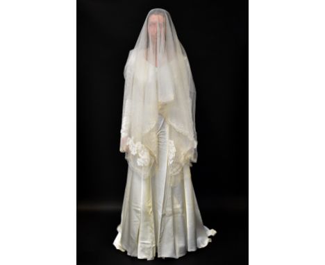 A 1960s full-length wedding dress, with fitted bodice and V-neck collar, long sleeves with long pointed buttoned cuffs, with 