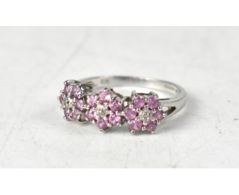 A 9ct white gold ring with three pink sapphire flowerheads, size N, approx 2.5g.